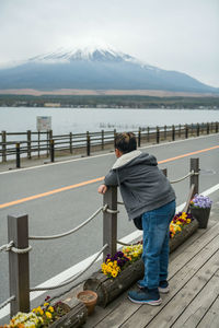 Young asian boy with hoodie sweatshirts at lake yamanakako look at mount fuji, yamanashi, japan.