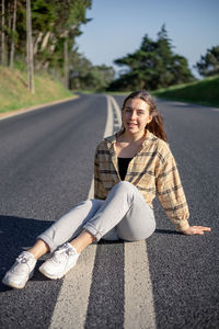 Portrait of young woman sitting on road