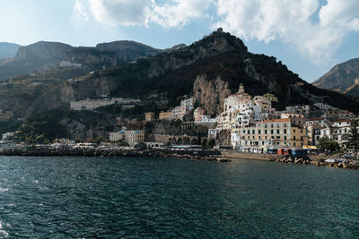 Scenic view of sea by mountains against sky