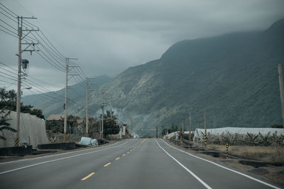 Road by mountains against sky