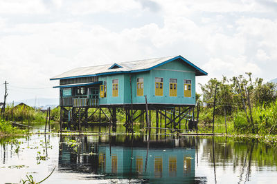 House by lake against sky