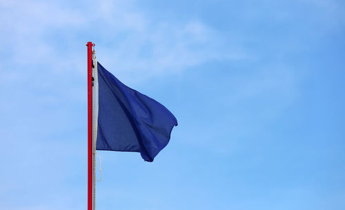 Big blue flag waves on the blue sky. this is a symbol indicates an area with clean sea