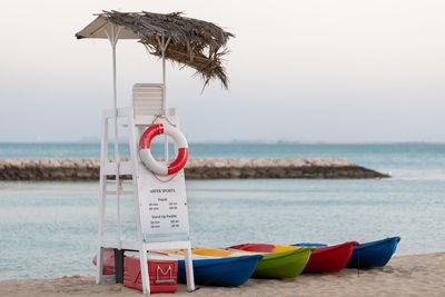 Deck chairs on beach against sky