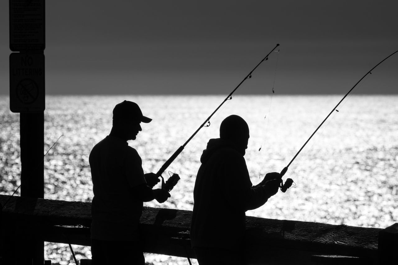 SILHOUETTE PEOPLE FISHING AT SEA AGAINST SKY