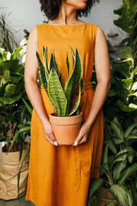 Midsection of woman standing by plant