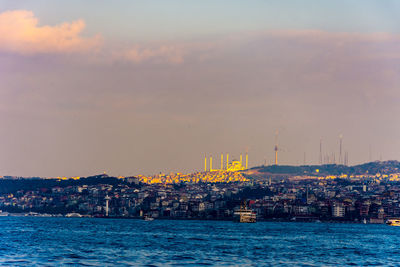 Sea by buildings against sky during sunset