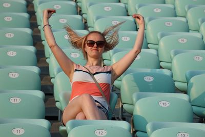 Low angle view of woman tossing hair while sitting on seat at stadium