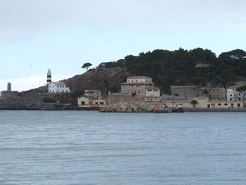 Buildings by sea against clear sky