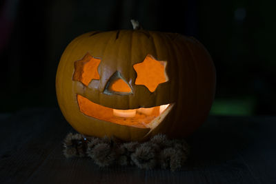 Close-up of illuminated pumpkin against orange wall during halloween