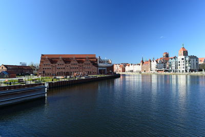 Buildings at waterfront against blue sky