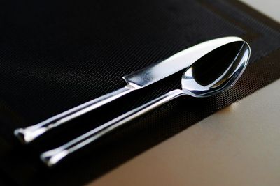 High angle view of spoon and table knife on napkin