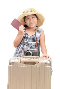 Portrait of smiling girl with suitcase and passport against white background