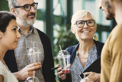 Multi-ethnic business people discussing while having refreshments in creative office