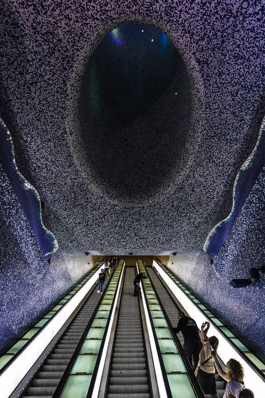 HIGH ANGLE VIEW OF PEOPLE ON ESCALATOR IN TUNNEL