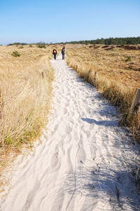 Rear view of women walking on sandy pathway