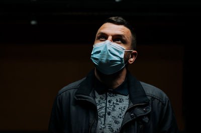 Portrait of man wearing a mask on dark black background