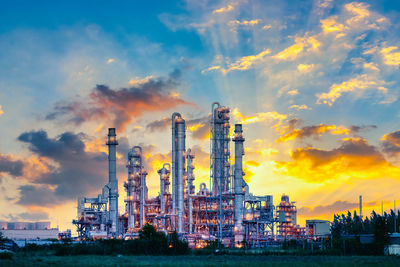 Low angle view of factory against sky during sunset