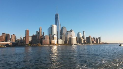 View of skyscrapers by sea against clear sky