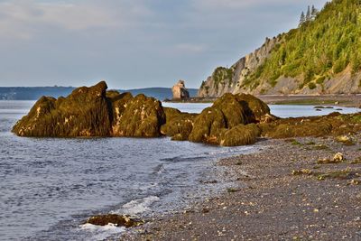 Rock formations on beach against sky