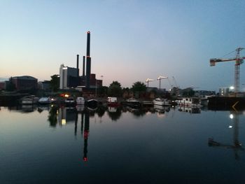 City by river against sky at dusk