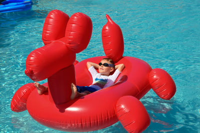 High angle view of boy relaxing on inflatable ring in swimming pool during sunny day