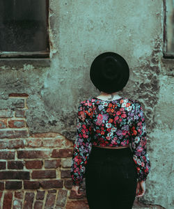 Rear view of woman standing against wall