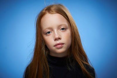 Close-up of young woman against blue background