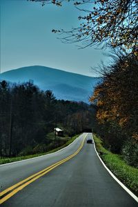 Road by trees against sky