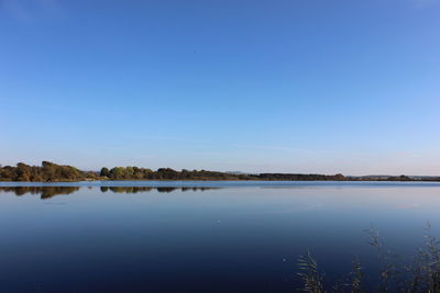 Scenic view of lake against clear blue sky