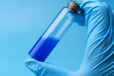Midsection of man holding bottle against blue background