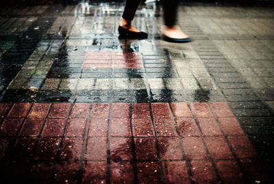 Blurred motion of woman walking on wet footpath during rainy season