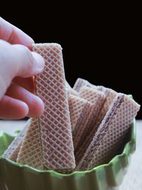 Close-up of hand holding wafer against black background