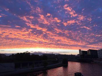 Silhouette of built structure against cloudy sky at sunset