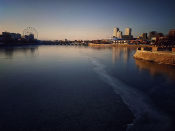 View of buildings by river against sky in city