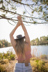 Woman with arms raised against trees