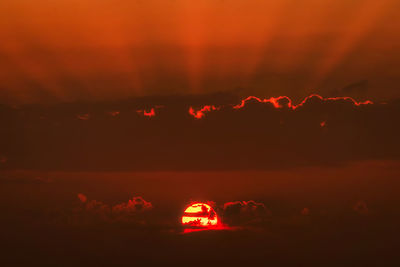 Illuminated red light against sky at sunset