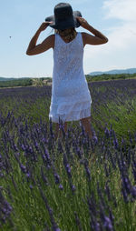 Rear view of woman standing on field against sky