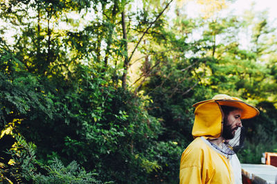 Beekeeper standing against trees