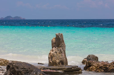 Scenic view of rocks by sea against sky