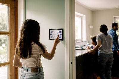 Girl using smart home app on digital tablet while standing near doorway