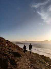 Rear view of women on beach against sky