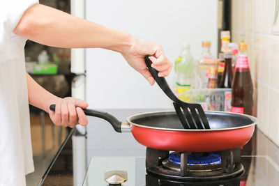 Cropped hands of woman frying food in kitchen