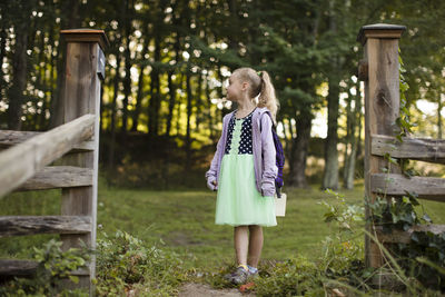 Full length of girl looking away while standing on grassy field