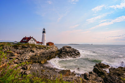 Lighthouse by sea against sky