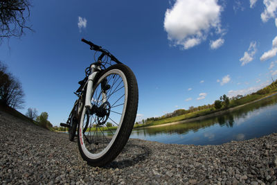 Low angle view of bicycle by lake against sky