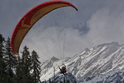 Rear view of man paragliding against snowcapped mountain