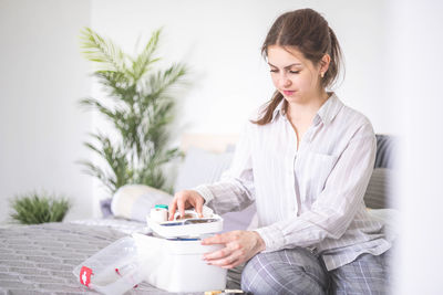 Young woman using mobile phone while sitting at clinic