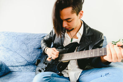 Man playing guitar while sitting on sofa