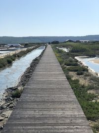 Boardwalk along landscape against clear sky