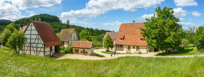 Panoramic shot of trees and houses on field against sky